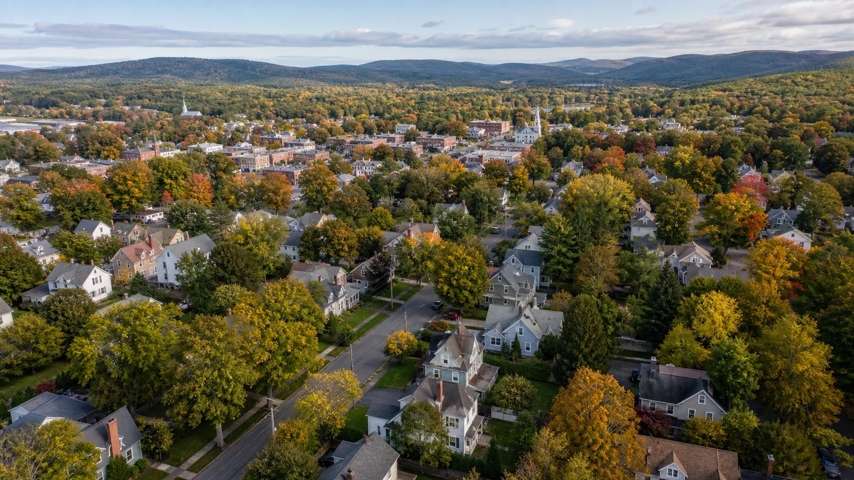 An aerial view of a Connecticut neighborhood and town center surrounded by autumn trees.